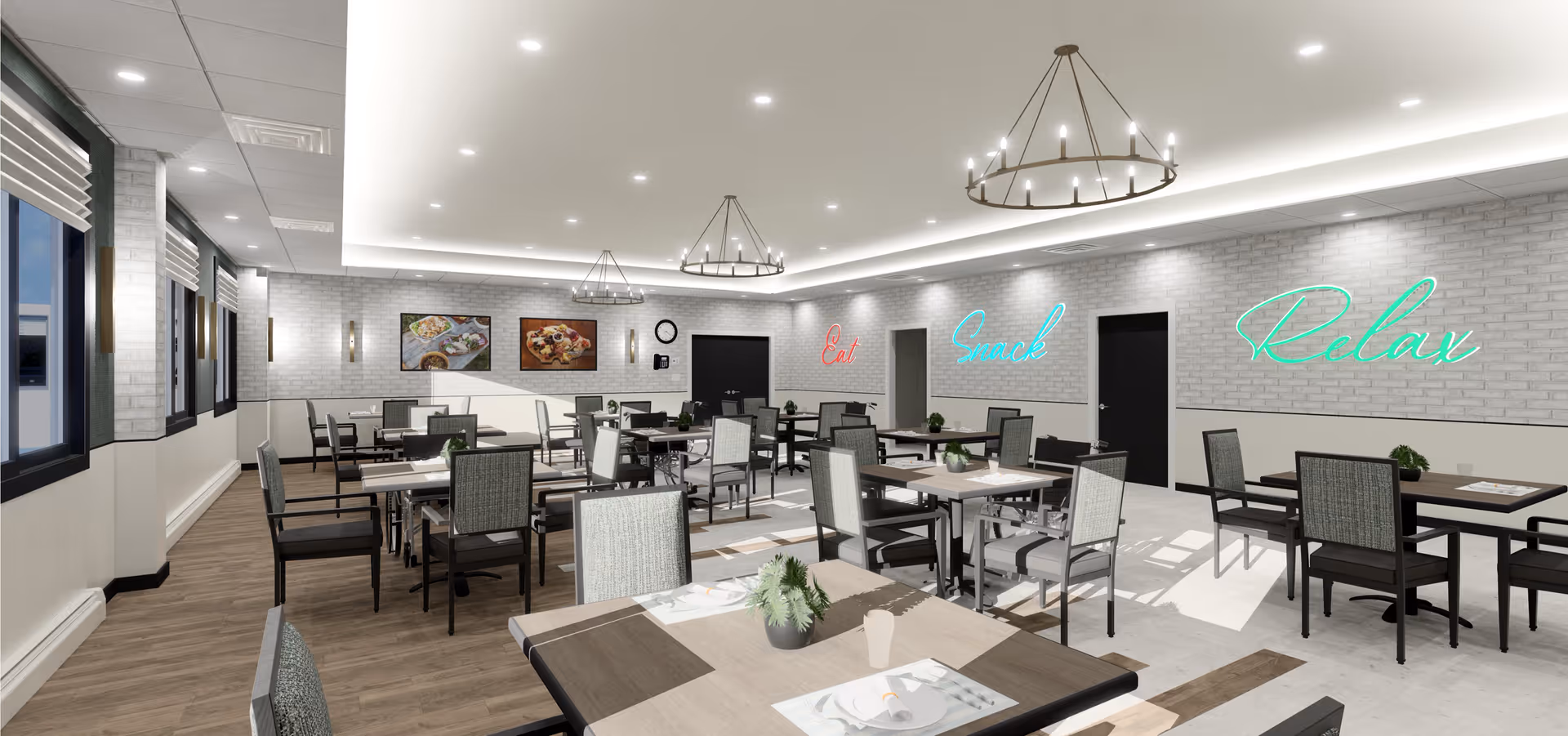 A spacious dining room with multiple tables and chairs arranged neatly. The room has large windows on one side with blinds, white brick walls, and modern ceiling lights including two circular chandeliers. Neon signs on the wall read 'Eat', 'Snack', and 'Relax'. There are framed pictures of food on the far wall and small potted plants on some tables.
