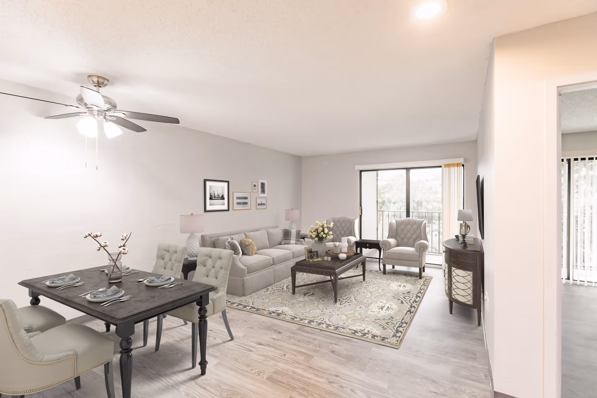 Open-plan living and dining area with a sofa, two armchairs, coffee table, dining table with place settings, and sliding glass door to a balcony.