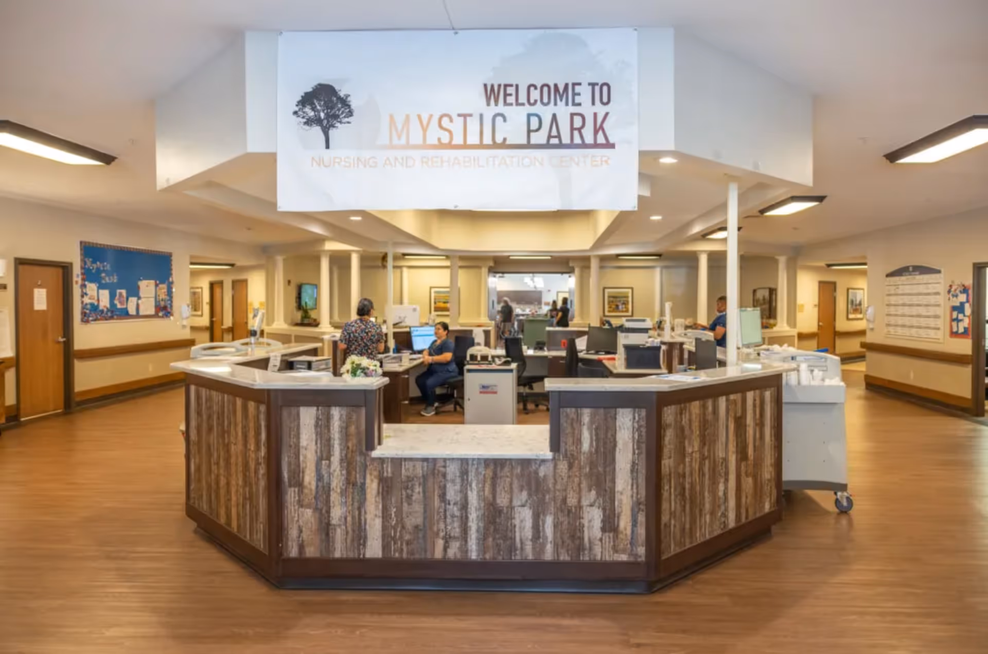 Reception area of Mystic Park Nursing and Rehabilitation Center with a welcome sign and staff at work.
