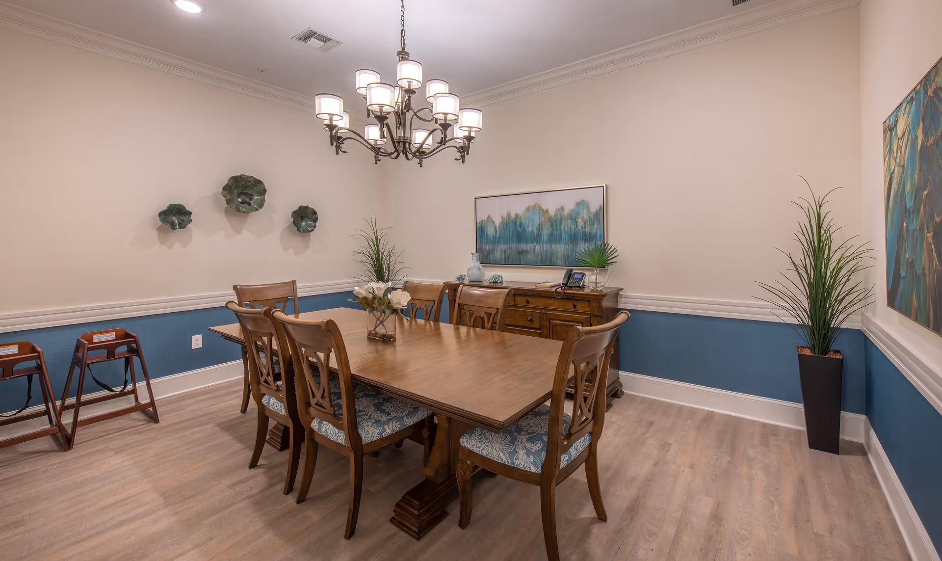 Elegant dining room with a wooden table and six chairs, chandelier, sideboard, and decorative wall art.