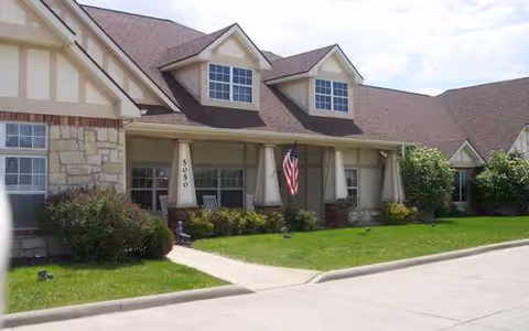 Exterior view of Bickford of West Des Moines senior living facility with lawn and flag.