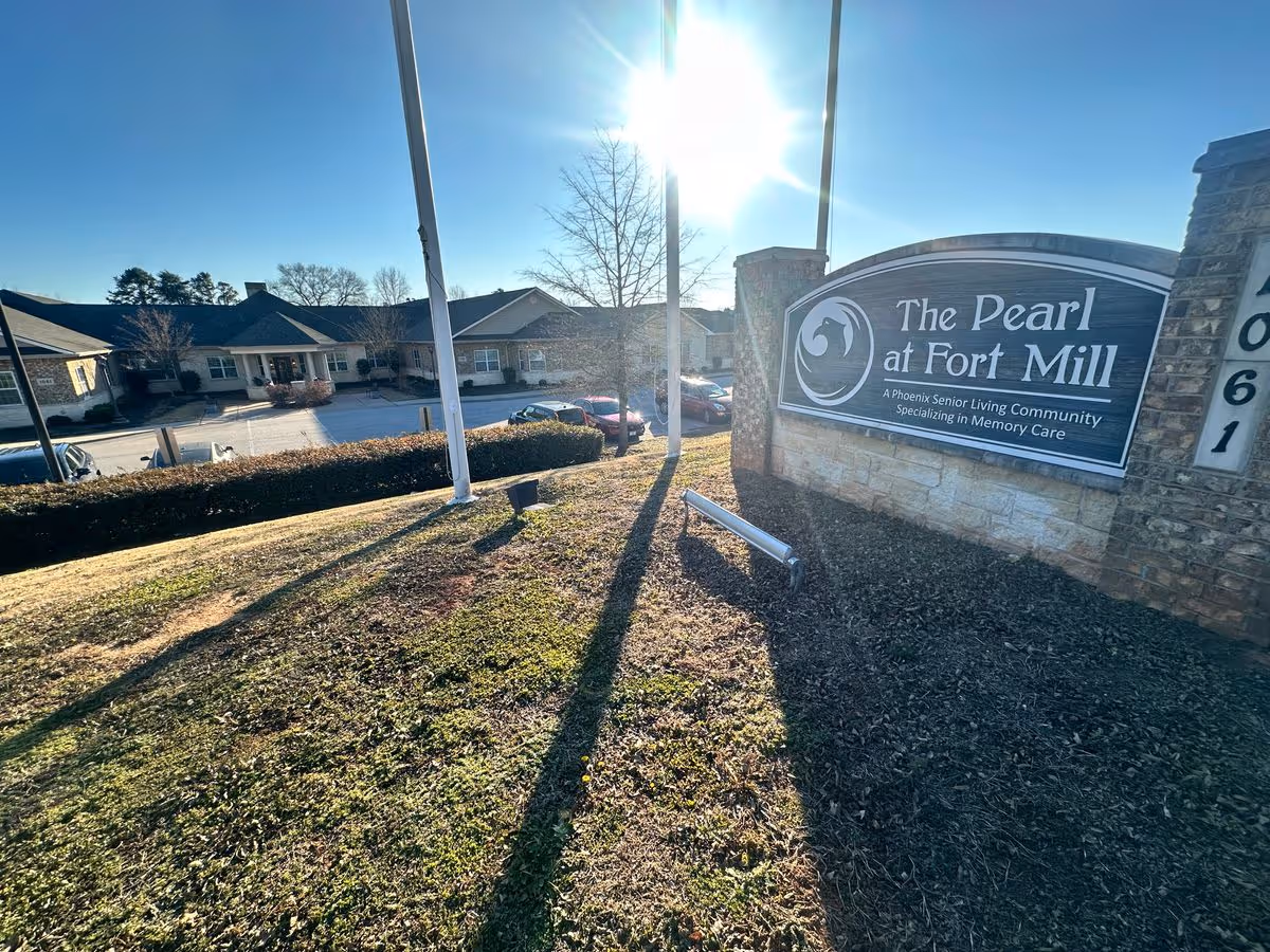 Entrance sign for The Pearl at Fort Mill in front of the senior living building on a sunny day