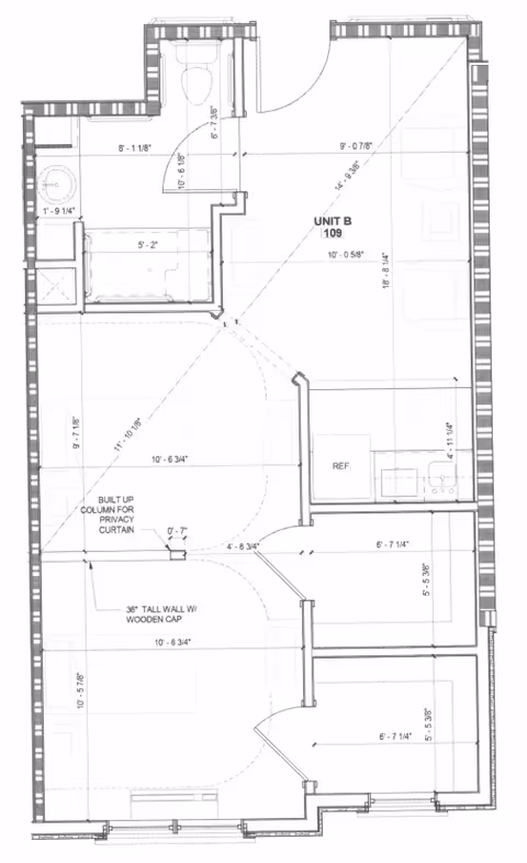 Architectural floor plan of Unit B 109 at Brickmont at Johns Creek showing layout with bathroom, kitchen area with refrigerator and sink, living space, and two separate rooms divided by walls and doors. Measurements and notes on built-up column for privacy curtain and tall wall with wooden cap are included.
