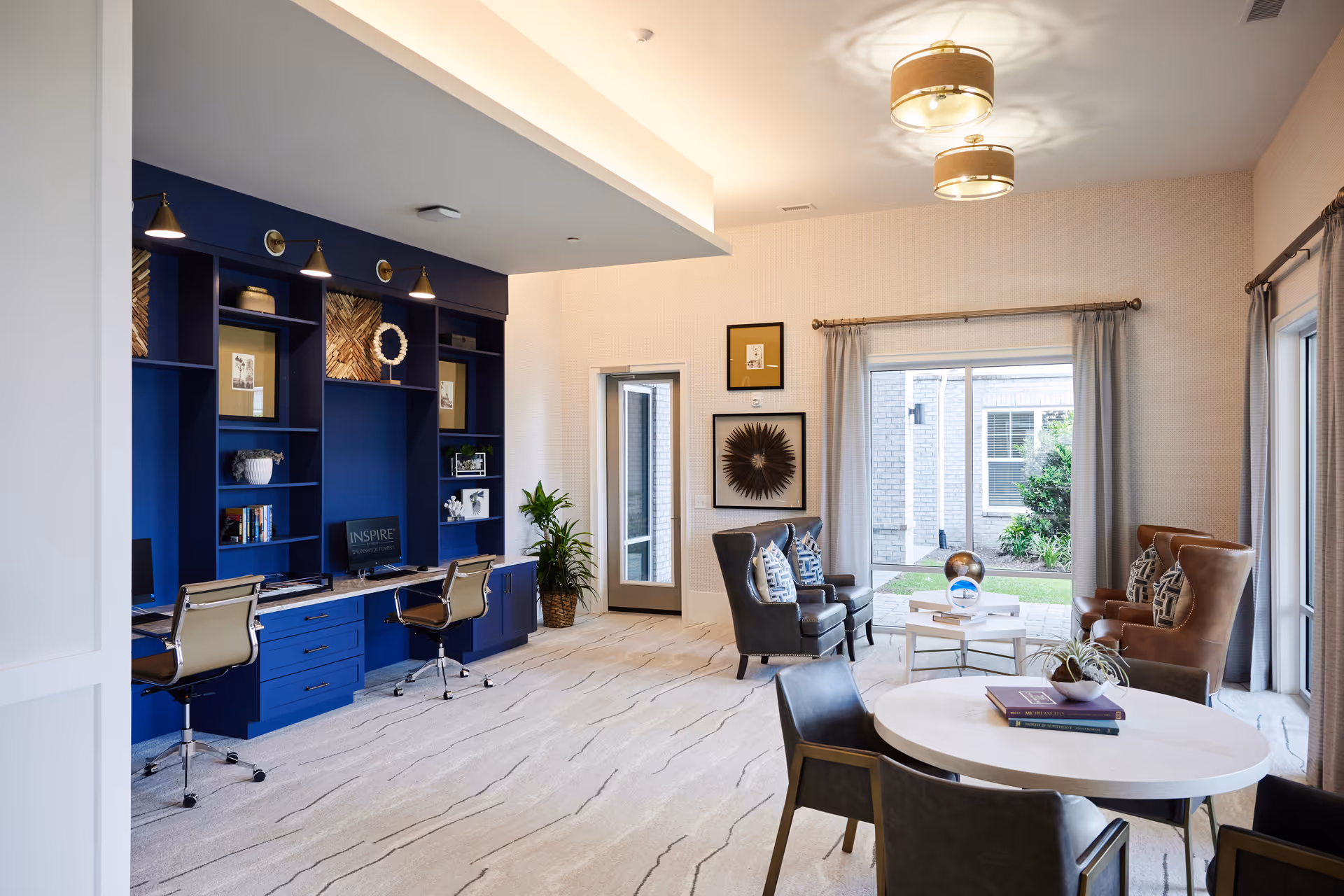 Bright lounge with blue built-in desks, chairs, and large windows to the outdoors.