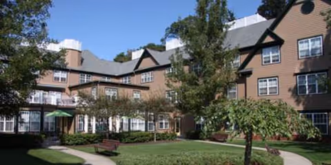 Cedar Mountain Commons exterior: a multi-wing building with a manicured courtyard and benches.