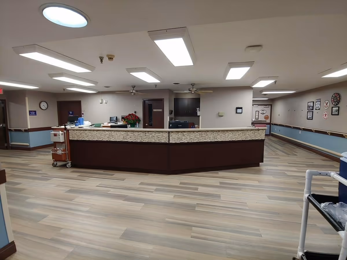 Wide view of an interior nursing station/reception desk in a senior living facility hallway.