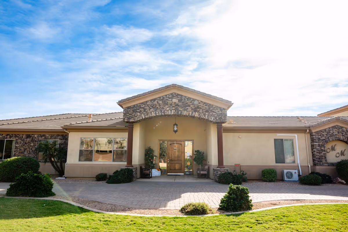 Exterior view of Moonlight Manor senior living facility with arched entrance and stone facade.