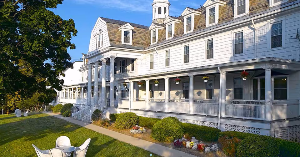 Front exterior of Celebration Villa of Manresa, white multi-story porch-lined building with manicured lawn.