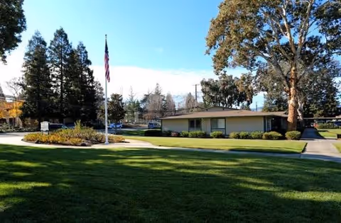Front exterior of Walnut Creek Manor with flagpole, lawn, and trees.