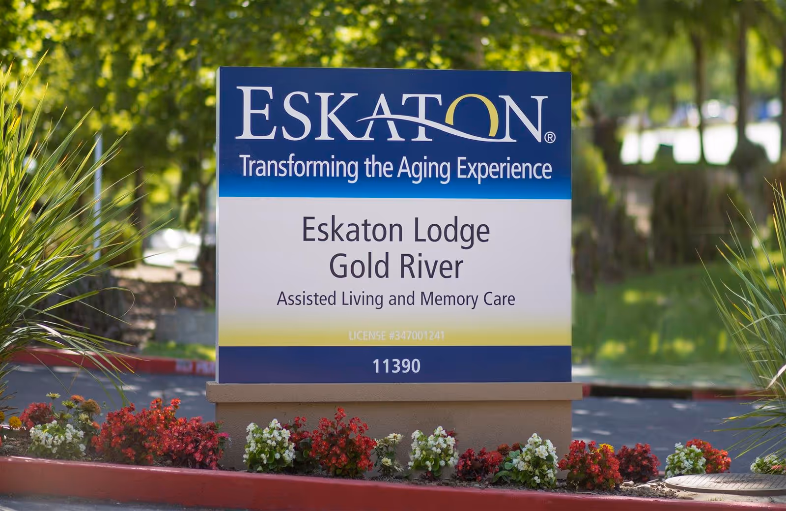 Outdoor sign for Eskaton Lodge Gold River, an assisted living and memory care facility, surrounded by flowers and greenery.