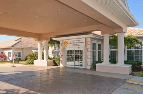 Covered entrance of Life Care Center Sarasota with columns and glass doors.