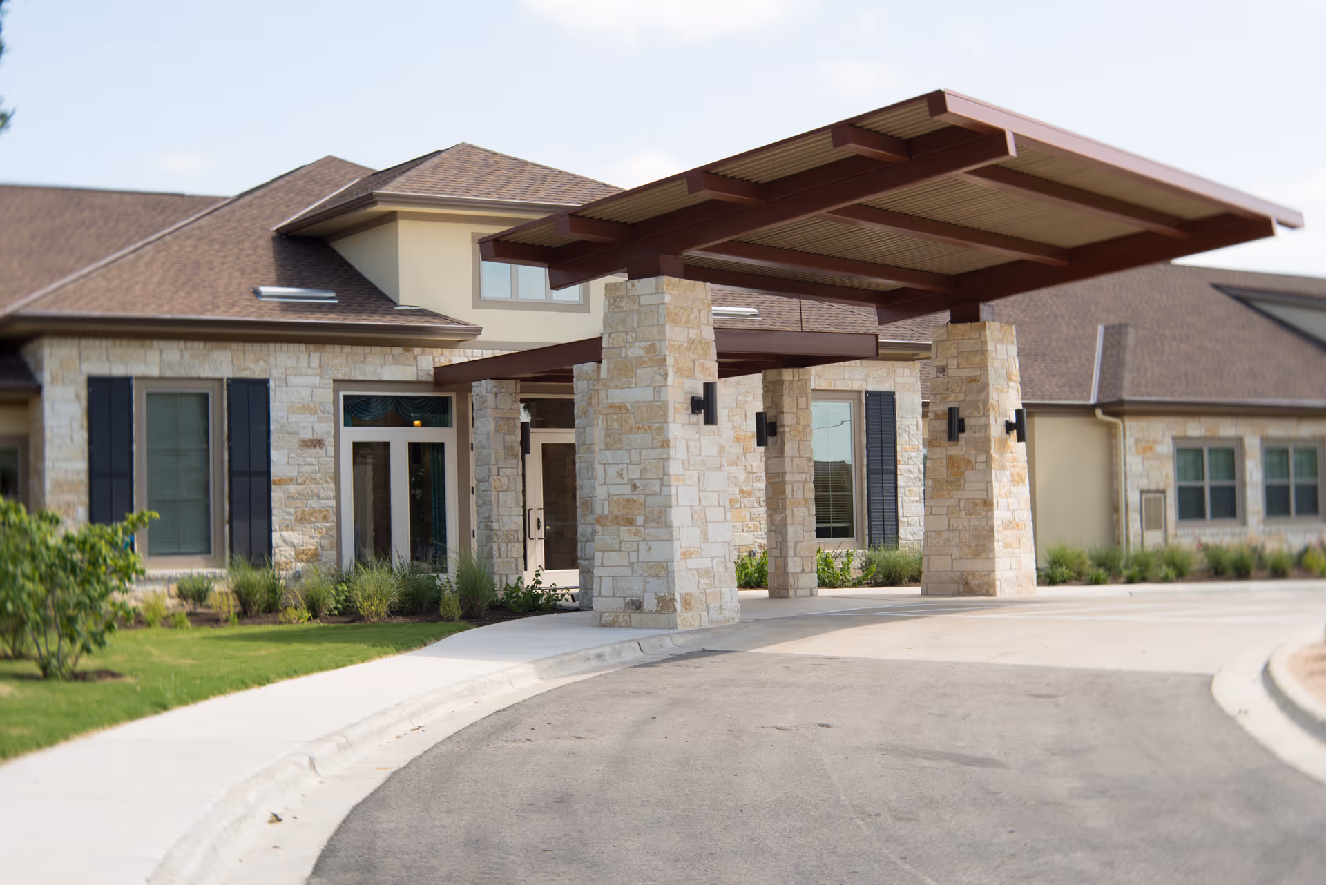 Senior living facility entrance with stone columns and a covered canopy.