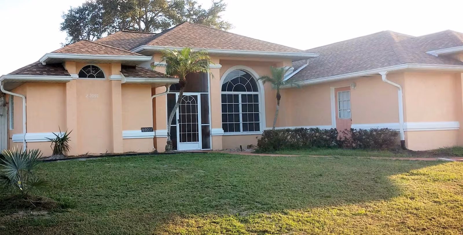 Peach-colored senior living facility exterior with arched windows and a lawn.