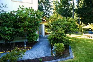 Exterior view of a facility entrance with a stone path and surrounding greenery.
