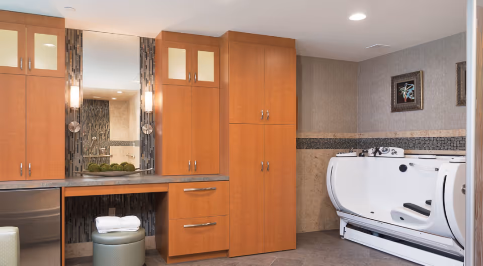 Spa-like bathroom with wooden cabinets, a large mirror, a padded stool with folded towels, and a white walk-in bathtub.
