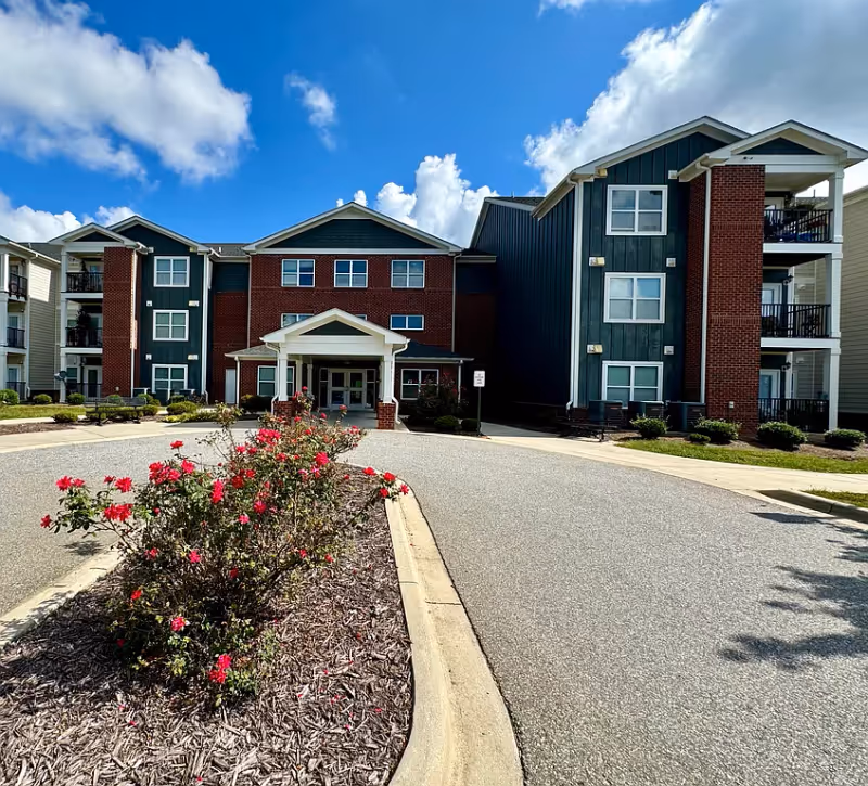 Exterior view of Villas at Hickory Tree, brick building with entrance and landscaped shrubs.
