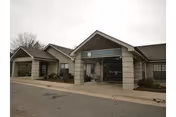 Front entrance of a single-story nursing and rehab center with a covered drop-off porte-cochère and landscaping.