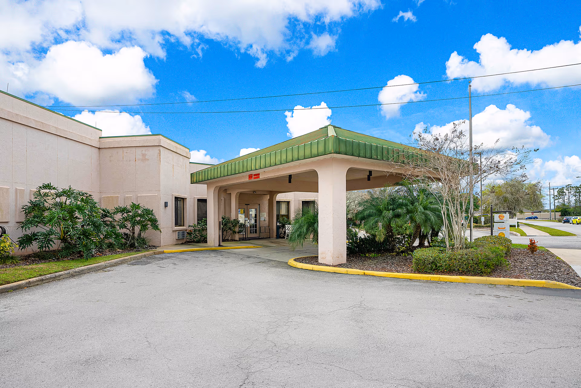 Front entrance of Highlands Lake Center with a covered porte-cochere, driveway and landscaping under a blue sky.