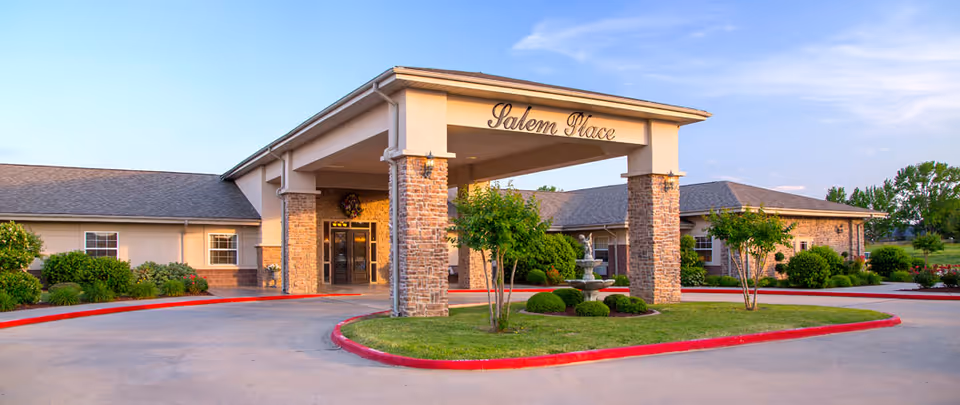 Front entrance of Salem Place Nursing and Rehabilitation Center featuring a covered porte-cochère, circular driveway, fountain, and landscaped grounds.