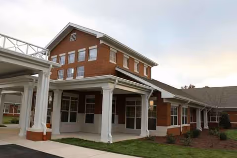 Front view of a brick senior living building with white columns and a covered entrance.