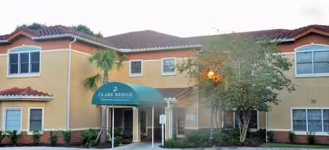 Exterior view of a tan senior living facility with a green entrance canopy.