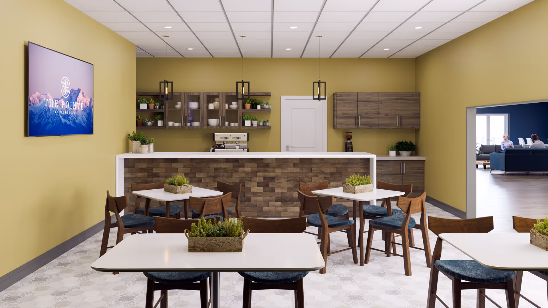 A dining area with several white tables and wooden chairs with blue cushions. Each table has a small rectangular planter with green plants. The back wall features a kitchen counter with a brick facade, wooden cabinets, shelves with dishes and plants, and a coffee machine. A flat-screen TV mounted on the left wall displays the logo for The Pointe at Meridian. Through an open doorway on the right, a lounge area with people sitting on sofas is visible.
