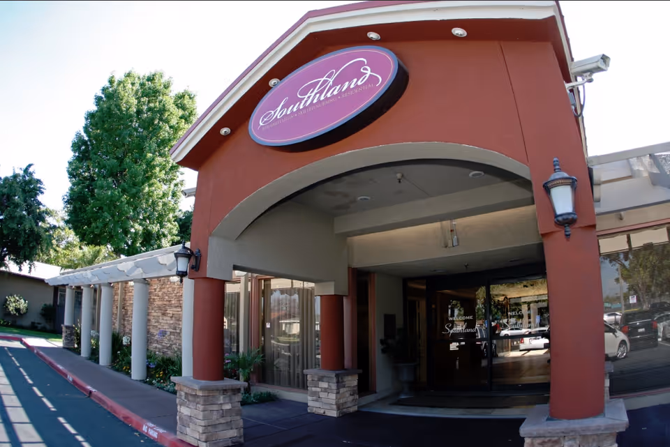 Covered entrance of the Southland Care Center with a round 'Southland' sign above columns and glass double doors.