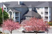 Exterior view of Valley View Retirement Community with pink flowering trees in front.