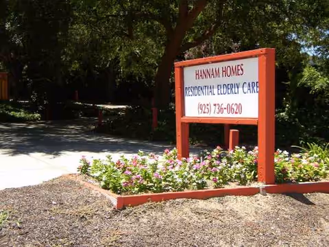 Red-framed sign for Hannam Homes Residential Elderly Care at a landscaped entrance.