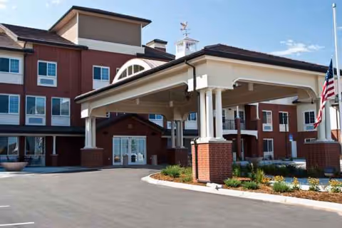 Exterior view of Lincoln Meadows Senior Living entrance with covered porte-cochere and brick facade.