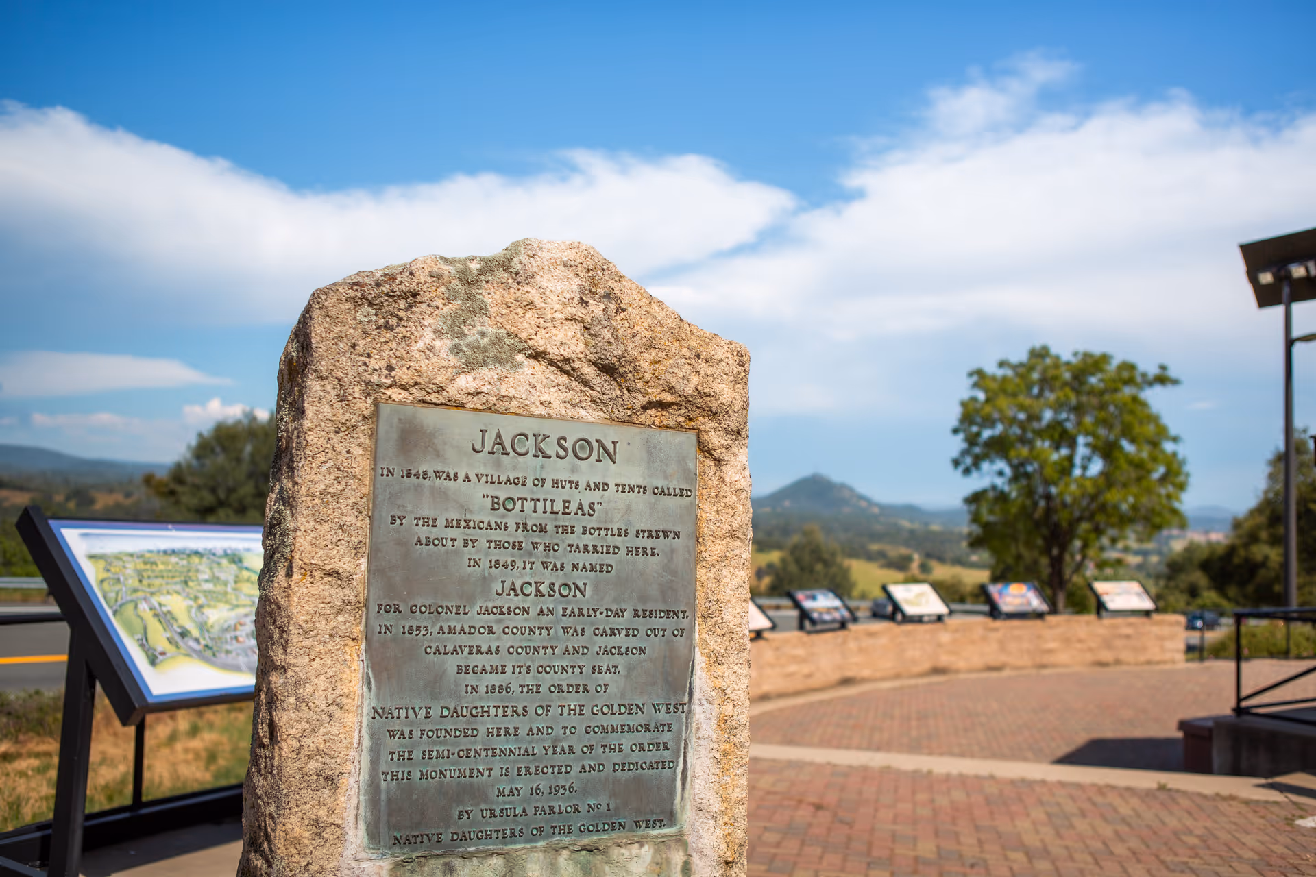 Stone historical marker titled "JACKSON" at a scenic outdoor overlook with informational panels and rolling hills under a blue sky.