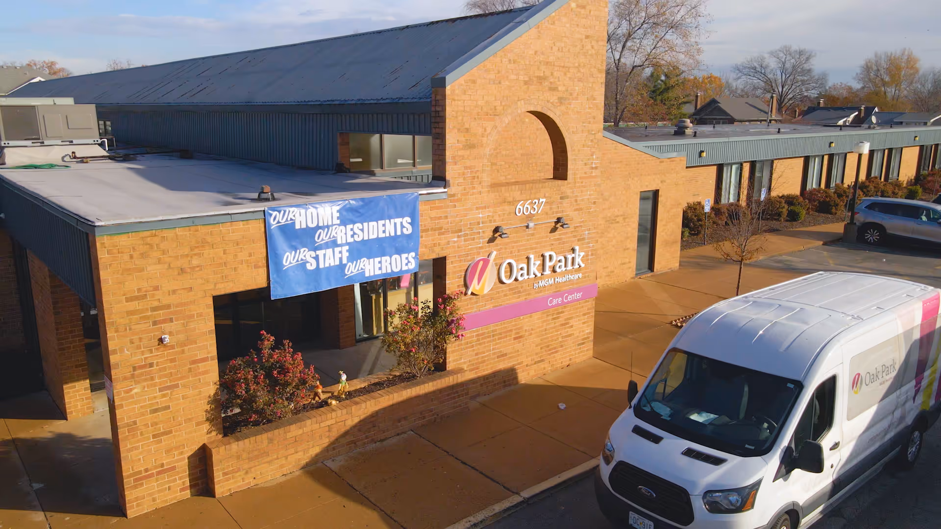 Front exterior of the Oak Park Care Center brick building with a banner and a branded van parked in front.