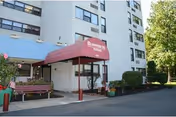 Front entrance of Bloomsburg Towers with maroon canopy and bench.