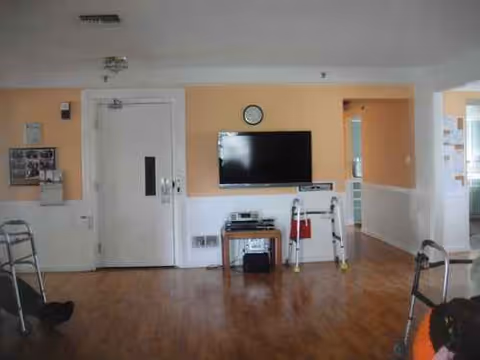 Bright common living room in a senior facility with a wall-mounted TV.