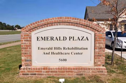 Brick sign reads Emerald Plaza and Emerald Hills Rehabilitation and Healthcare Center in front of building.