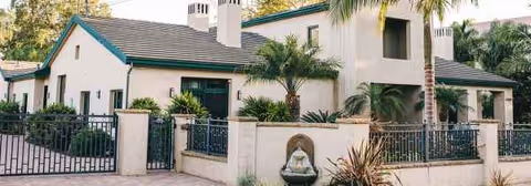 Exterior view of Abundant Care III senior living facility with gate and palm trees.