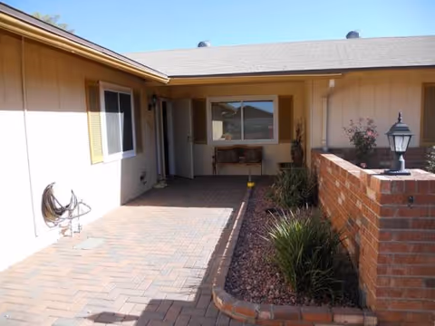 Front entrance courtyard of a beige assisted living home with brick planter and lamp