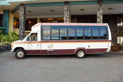 A white and maroon passenger bus parked in front of Life Care Center of Hilo.