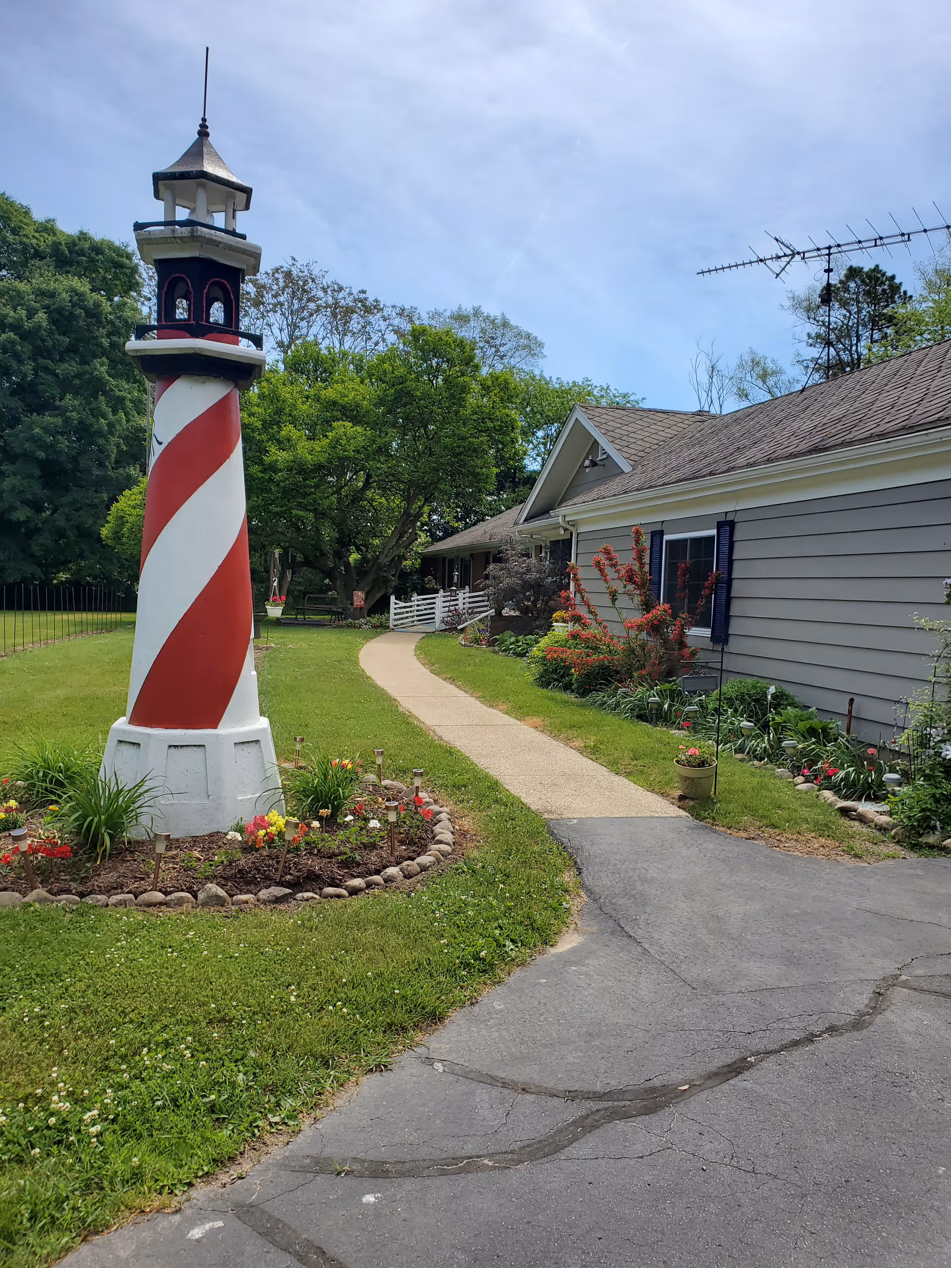 A decorative lighthouse stands in a garden pathway leading to Gull Arbor Senior Living.