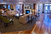 Spacious furnished common lounge with sofas, armchairs, coffee tables, a fireplace and hardwood floors.