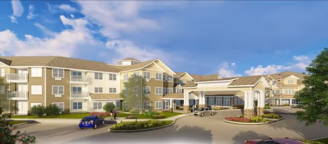 Exterior view of a large, multi-story senior living facility with beige and white siding, multiple windows, and a covered entrance driveway. Several cars are parked near the entrance, and a few people are walking on the sidewalk. The sky is blue with some clouds.