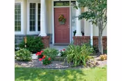 Front entrance of a building with a red door, columns, and landscaped greenery.