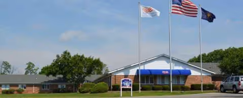 Front view of Rosebud Village facility with flags and blue awning