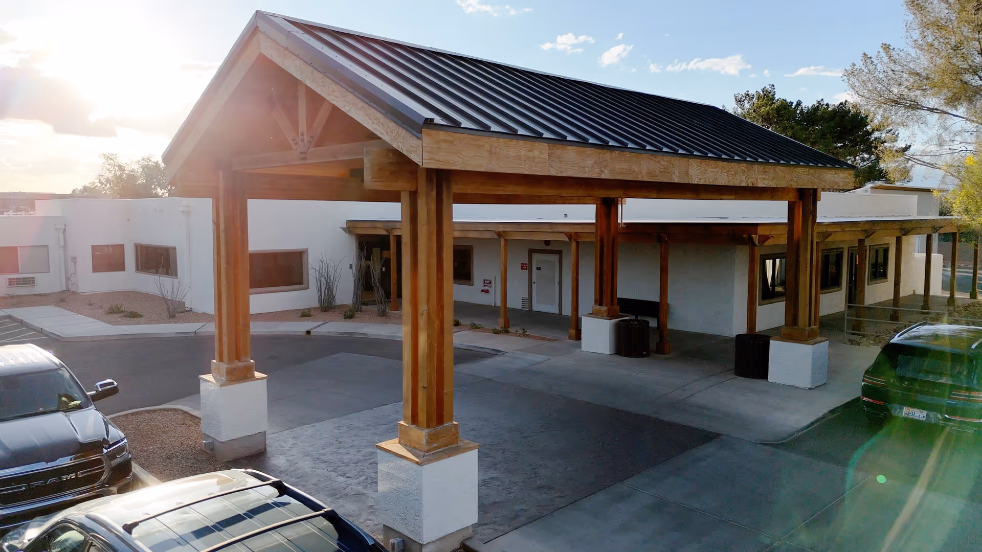 Exterior view of Haven Health Sierra Vista showing a covered entrance with wooden beams and a metal roof, surrounded by parked cars and a single-story building with white walls and windows.