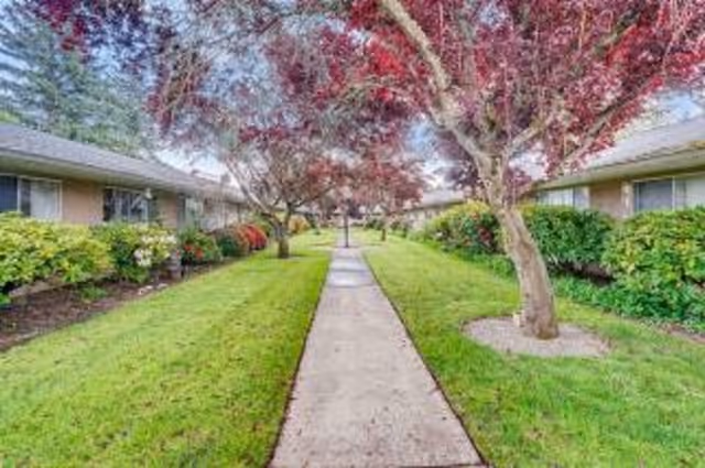 A walkway through a landscaped courtyard between low-slung retirement buildings with trees and shrubs.