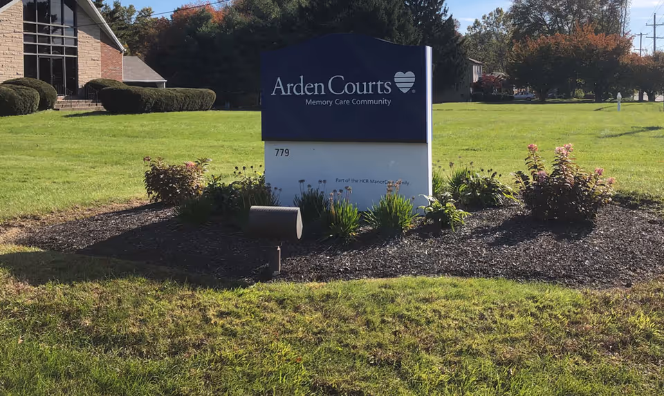 Exterior view of the Arden Courts building sign surrounded by landscaped grass and flowers.