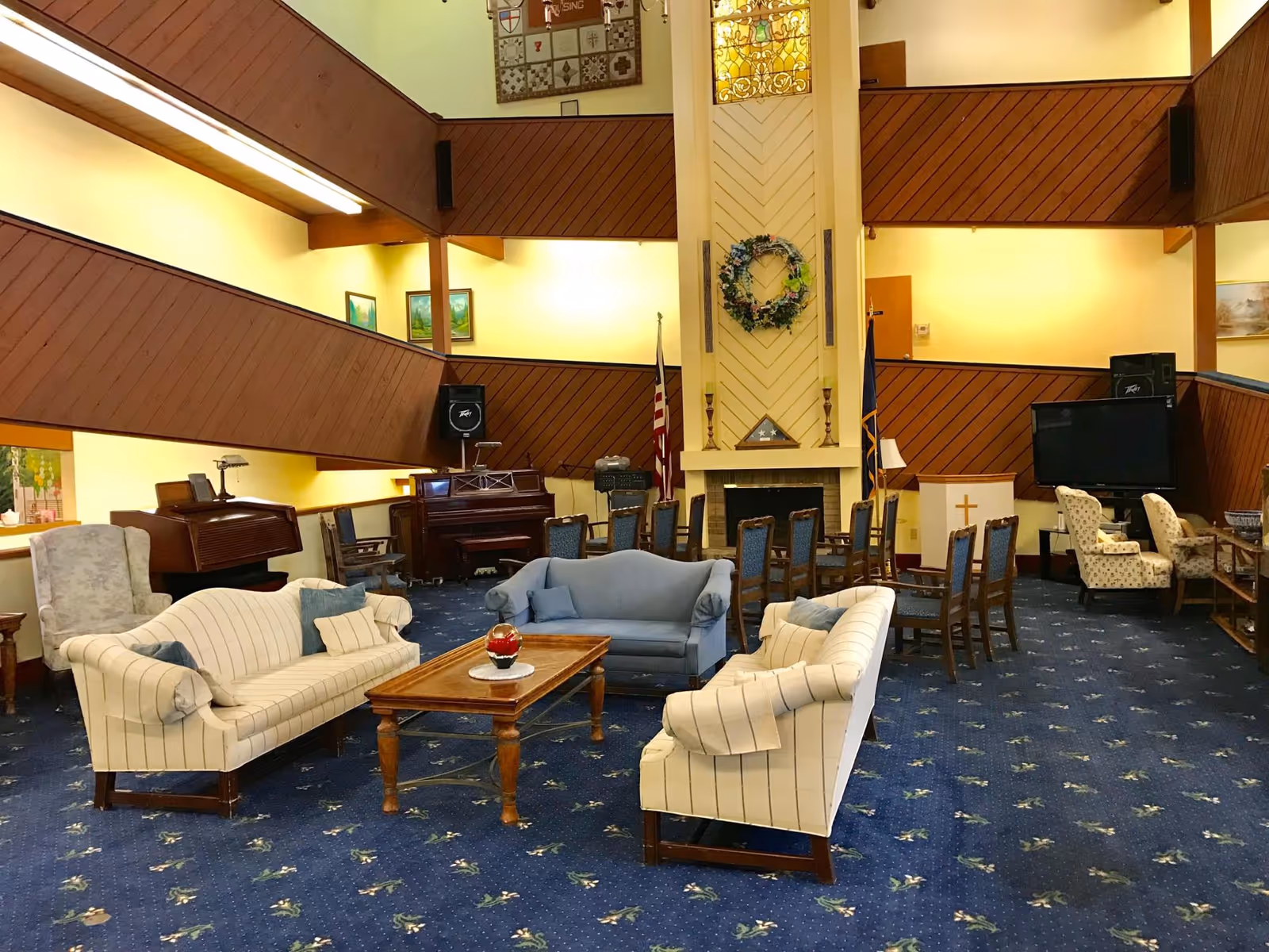 Open multi-level common lounge with sofas, chairs, a fireplace, piano and TV.