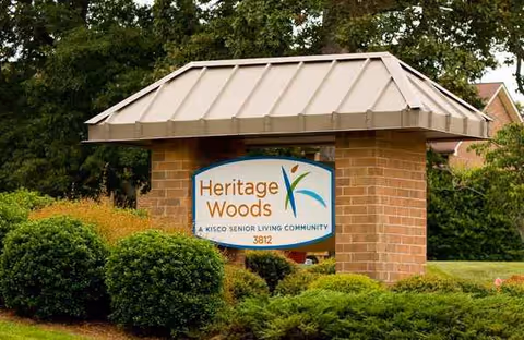 Exterior view of Heritage Woods sign on brick entrance pillar with landscaping