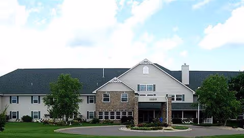 Front view of Ridgeview Place Assisted Living building with entry, stone accents, and surrounding greenery.
