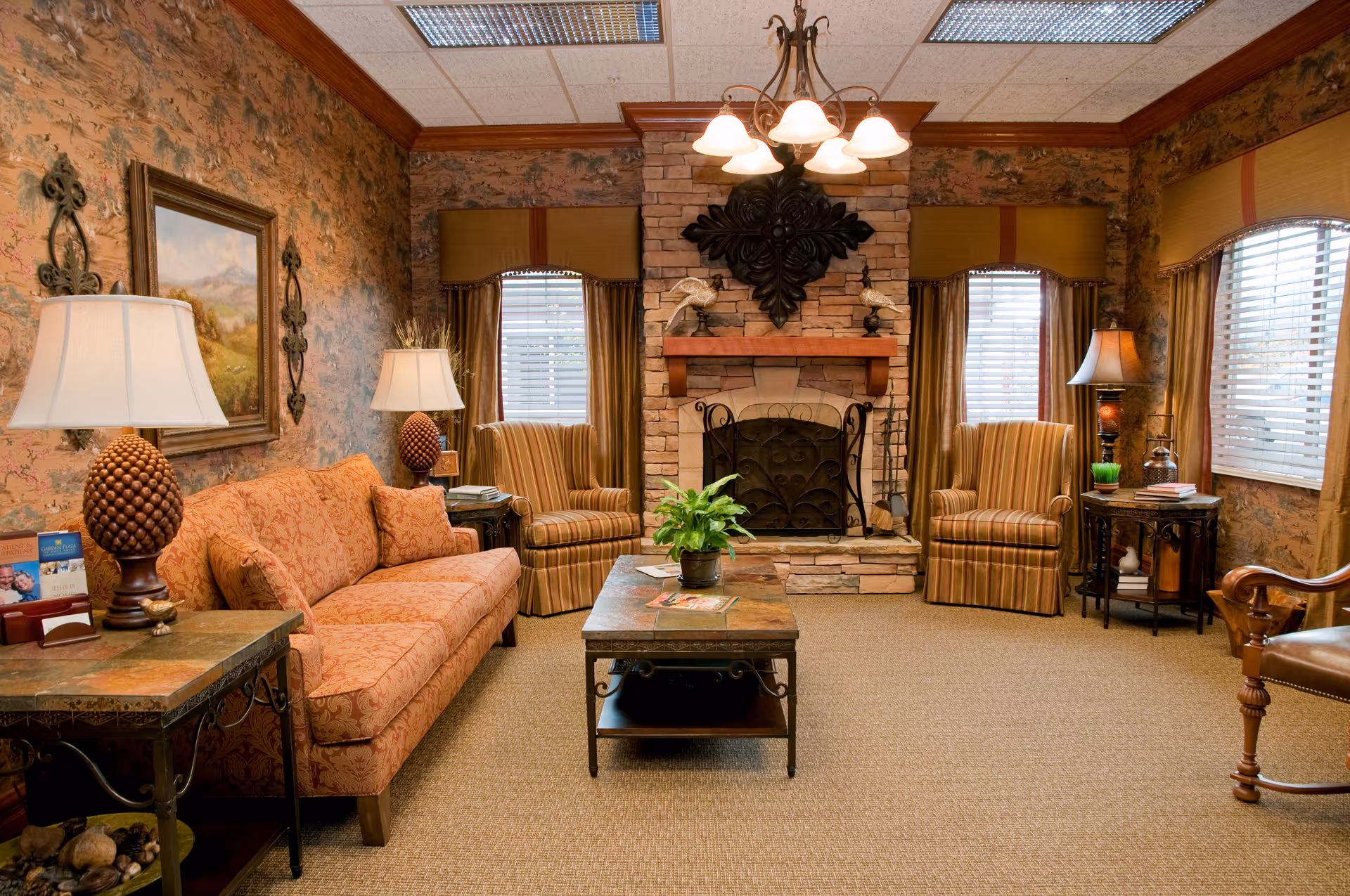Warm, traditionally decorated sitting room with a sofa, armchairs, coffee table, and a stone fireplace.